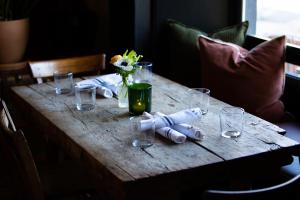 une table en bois avec des verres et un vase de fleurs. dans l'établissement Imperial Hotel + Restaurant, à Amador City