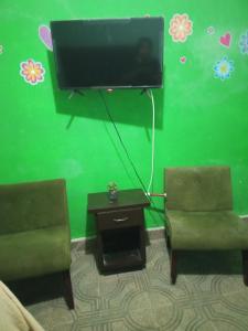 a living room with two chairs and a flat screen tv at Recamara confortable en San Nicolás in Monterrey