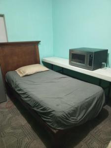 a bed in a room with a microwave on a counter at Recamara confortable en San Nicolás in Monterrey