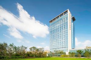 un grand bâtiment avec un ciel bleu et des nuages dans l'établissement Sheraton Langfang Chaobai River Hotel, à Dachang
