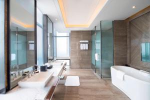 un bagno con tre lavandini, vasca e specchi di Sheraton Langfang Chaobai River Hotel a Dachang