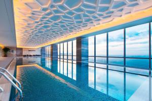 a hotel swimming pool with a view of the water at Sheraton Langfang Chaobai River Hotel in Dachang