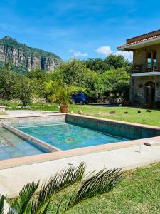 a swimming pool in front of a house with mountains in the background at Hotel Boutique Jardín de Flores in Tlayacapan