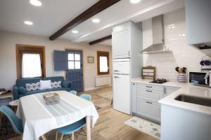 a kitchen and dining room with a white table and chairs at Casa Regente in O Viso