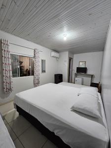 a large white bed in a room with a window at Aconchego Lar Cama e Café in Foz do Iguaçu
