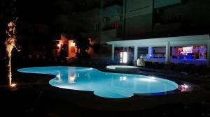 
a room with a pool and lights on at Quayside Village Hotel in Kavos
