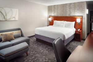 una camera d'albergo con letto e sedia di Courtyard by Marriott Atlanta Airport South/Sullivan Road ad Atlanta