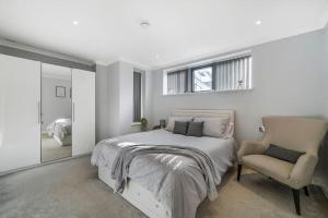 ein Schlafzimmer mit einem Bett, einem Stuhl und einem Fenster in der Unterkunft Brentford's Oasis with Gated Parking in Brentford