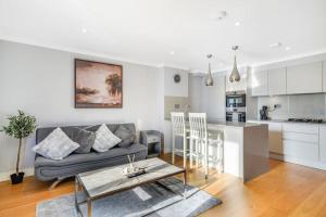 ein Wohnzimmer mit einem Sofa und einer Küche in der Unterkunft Brentford's Oasis with Gated Parking in Brentford