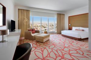 アブダビにあるマリオットホテル ダウンタウン アブダビのベッドとテレビが備わる広いホテルルームです。