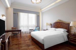 a bedroom with a large white bed and a desk at Delta Hotels by Marriott Shanghai Baoshan in Baoshan