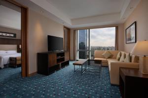 a hotel room with a couch and a bed and a television at Courtyard by Marriott Suzhou in Suzhou