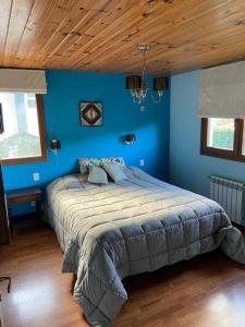 1 dormitorio con 1 cama grande en una pared azul en La casa de la colina en San Carlos de Bariloche