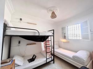 Ce dortoir comprend 2 lits superposés et une fenêtre. dans l'établissement WELKAM Home & Coworking, à Essaouira