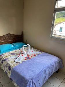 Pousada Zacarias في أورو بريتو: غرفة نوم عليها سرير وبجعة