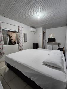 a large white bed in a room with a window at Aconchego Lar Cama e Café in Foz do Iguaçu