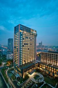 a tall building with lights on in a city at Renaissance Shanghai Caohejing Hotel in Shanghai