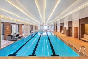 - une grande piscine d'eau bleue dans un bâtiment dans l'établissement Renaissance Shanghai Caohejing Hotel, à Shanghai