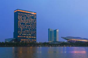 een hoog gebouw naast een waterlichaam bij Renaissance Suzhou Wujiang Hotel in Suzhou