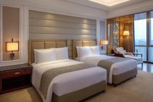 The Ritz-Carlton, Chengdu في تشنغدو: سريرين في غرفة الفندق مع نافذة كبيرة