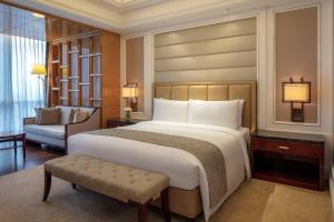 um quarto com uma grande cama branca e uma cadeira em The Ritz-Carlton, Chengdu em Chengdu