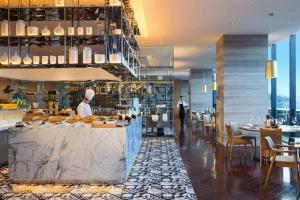 ein Restaurant mit einem Koch, der Essen auf einer Theke zubereitet in der Unterkunft Renaissance Suzhou Wujiang Hotel in Suzhou