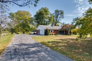 a driveway leading to a red house with trees at Quaint Economy Retreat with Patio and Spacious Yard! 