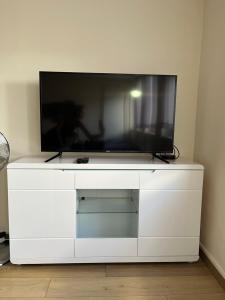a flat screen tv sitting on top of a white dresser at Chic studio Courbevoie Paris in Courbevoie