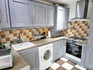 a kitchen with white cabinets and a washing machine at Moston, Manchester in Manchester