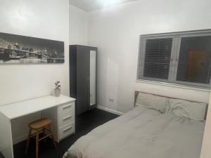 a white bedroom with a desk and a bed at Cosy central apartment near Stokes Croft in Bristol