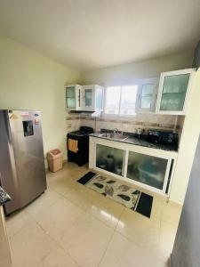 una cocina con nevera de acero inoxidable y armarios blancos en Oasis de Paz 4, en Jarabacoa