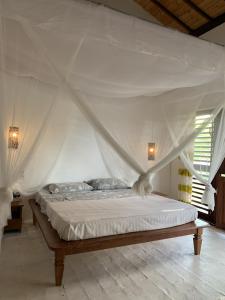 una camera da letto con un letto bianco con baldacchino di Casa Vagalume - 10 minutes to secluded beach a Pôrto de Pedras