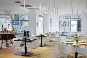 a restaurant with tables and white chairs and windows at Element Chongli in Chongli