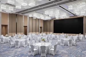 a conference room with white tables and chairs and a screen at Courtyard by Marriott Qinhuangdao West in Qinhuangdao