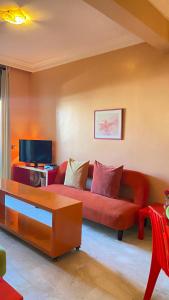 ein Wohnzimmer mit einem roten Sofa und einem TV in der Unterkunft Plage Skhirat appartement amis et familles in Skhirat