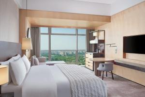 um quarto de hotel com uma cama grande e uma secretária em Le Meridien Zhongshan em Zhongshan