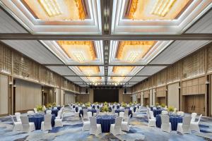 昆明市にあるSheraton Kunmingのテーブルと白い椅子と天井が備わる広い客室です。