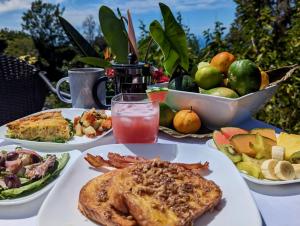 a table topped with plates of food and fruit at Mango Sunset Bed and Breakfast in Kailua-Kona