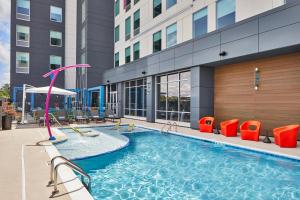 - une piscine avec des chaises et un toboggan dans un bâtiment dans l'établissement Aloft Chattanooga Hamilton Place, à Chattanooga