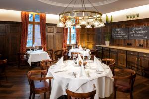 una sala da pranzo con tavoli, sedie e lampadario a braccio di Dorint Am Goethepark Weimar a Weimar