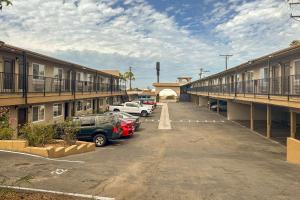 un aparcamiento con coches estacionados frente a los edificios en Rodeway Inn National City San Diego South, en National City