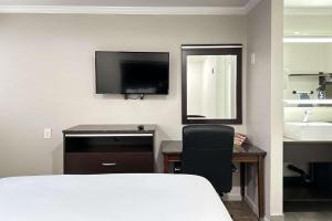 a bedroom with a desk and a bed and a television at Rodeway Inn National City San Diego South in National City