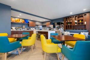 a restaurant with yellow and blue chairs and tables at Comfort Inn & Suites Houma in Houma