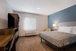a bedroom with a bed and a flat screen tv at WoodSpring Suites Moreno Valley in Moreno Valley
