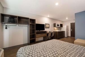 a bedroom with a bed and a desk with a television at WoodSpring Suites Moreno Valley in Moreno Valley