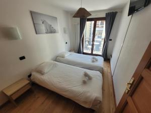 two beds in a small room with a window at 4-star apartments in Chamonix centre with free private parking in Chamonix