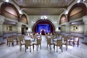 Habitación grande con mesas, sillas y un escenario en Alhambra Palace Hotel, en Granada