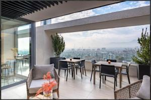 a balcony with tables and chairs and a view of the city at Cómodo Departamento 1D1B para dos personas in Santiago
