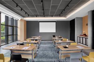 uma sala de aula com mesas de madeira e um ecrã branco em Moxy Shanghai Hongqiao NECC em Xangai