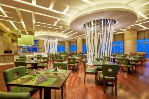 a restaurant with tables and green chairs and windows at The Westin Nanjing Xuanwu Lake in Nanjing